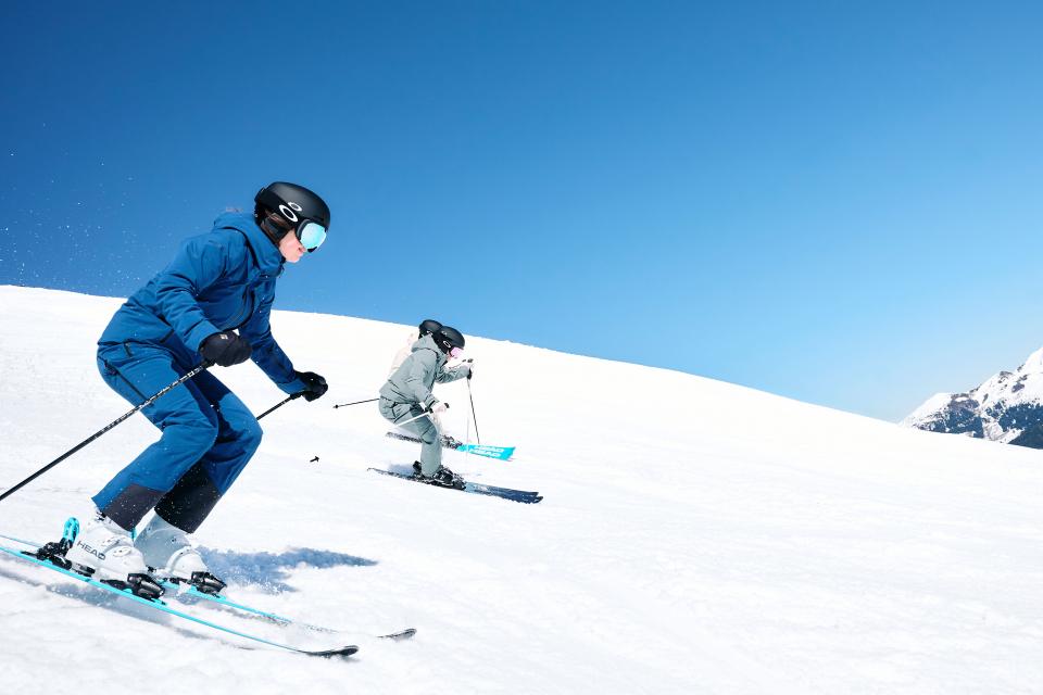 Two well-equipped skiers are skiing down the mountain.