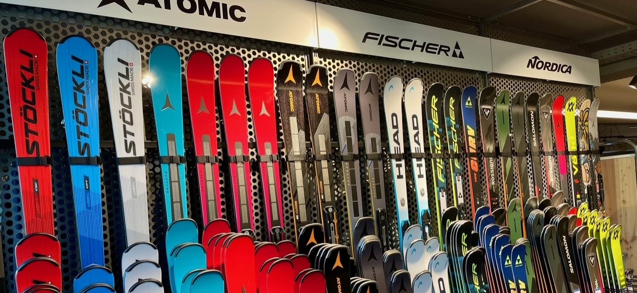 Ausstellung neuer Skier der Marken Stockli, Atomic, Fischer, Head und Nordica zum Verkauf in einem Skigeschäft.