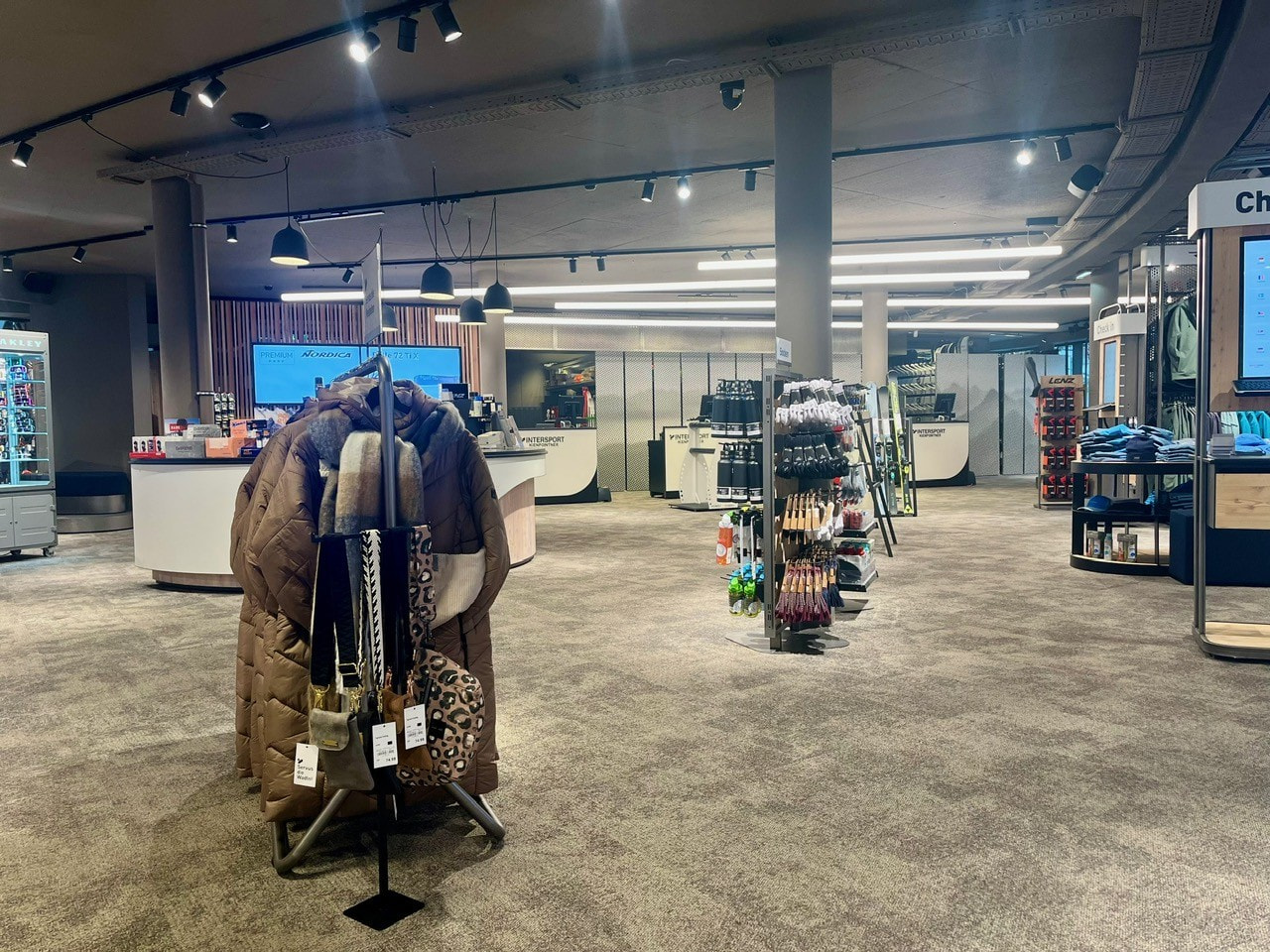 Modern retail store interior with clothing racks, displays, and bright overhead lighting for shopping.